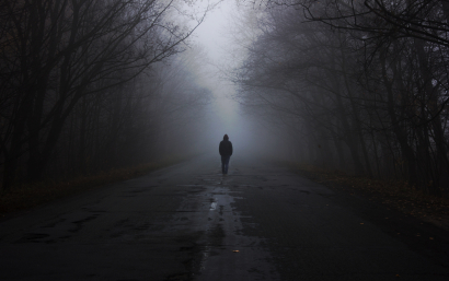Man in a fog walks down the ro...